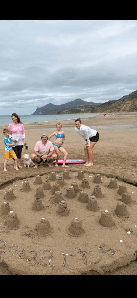 Grace posing triumphantly in front of the Hogwarts model built by the family on the Wales holiday — confidence and joy filling the frame