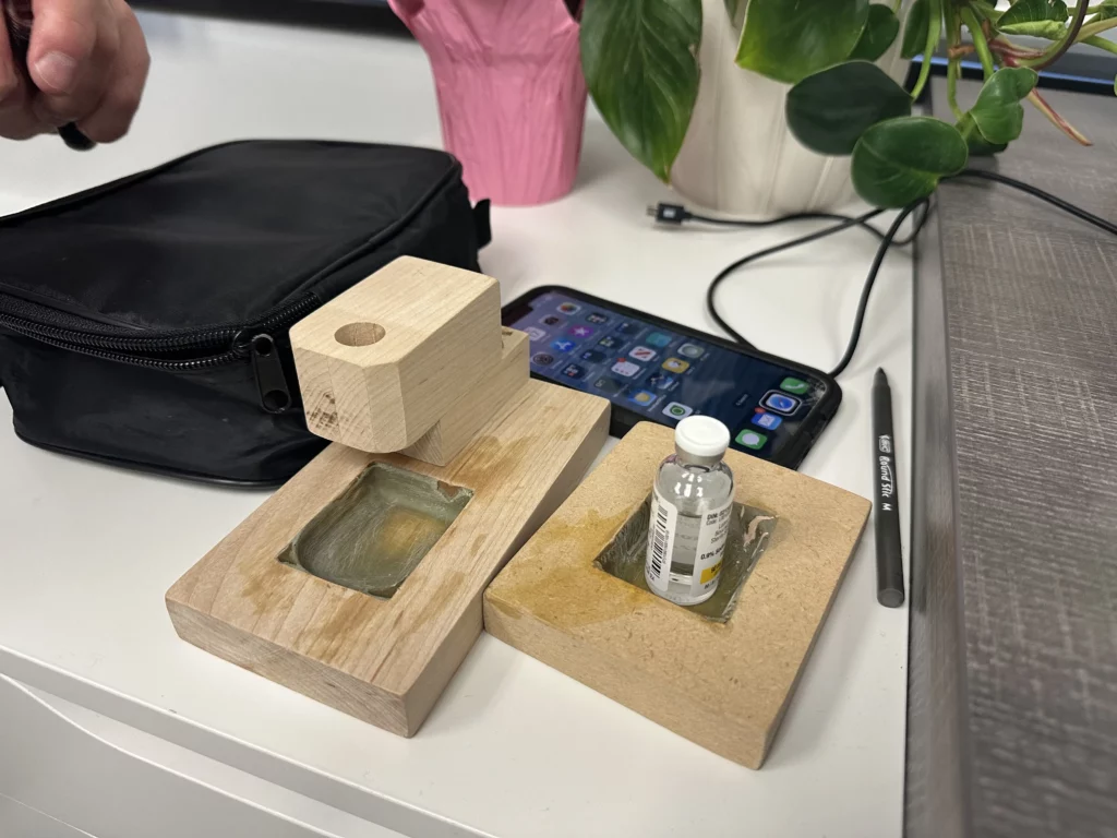 Roger's handcrafted wooden tactile pod-filling station with carved wells to hold the pod and insulin vial in fixed positions