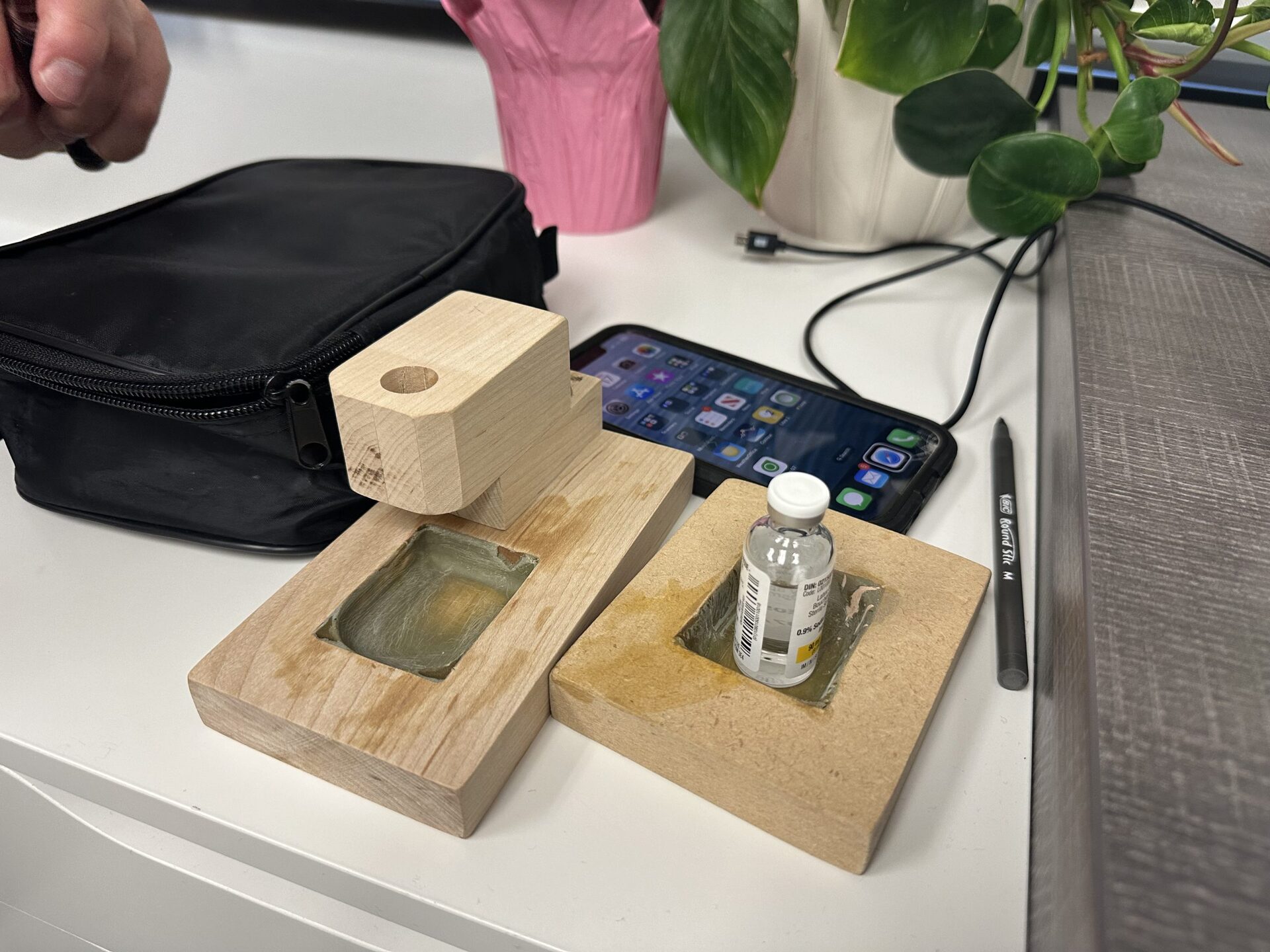 Custom wooden tactile pod-filling station with carved wells that hold the pod and insulin vial in fixed positions, preventing misalignment